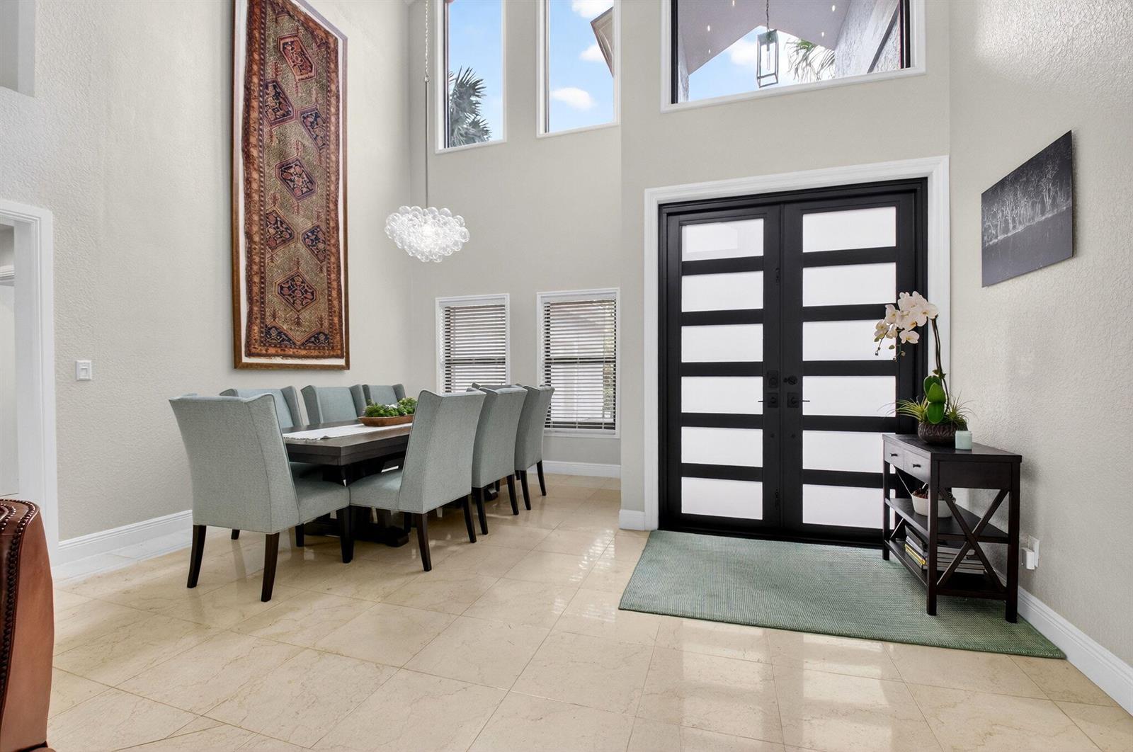 A dining area with a tall tapestry, light blue chairs, and double front entry doors — 10655 Rio Hermoso, Delray Beach FL 33446, DELRAY BEACH, FL