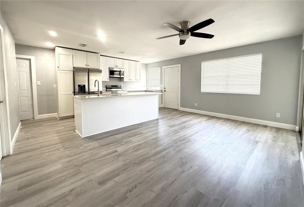 A kitchen with white cabinets, stainless steel appliances, and a center island, featuring wood-look flooring — 1231 ILLINOIS AVENUE UNIT 1, PALM HARBOR, FL
