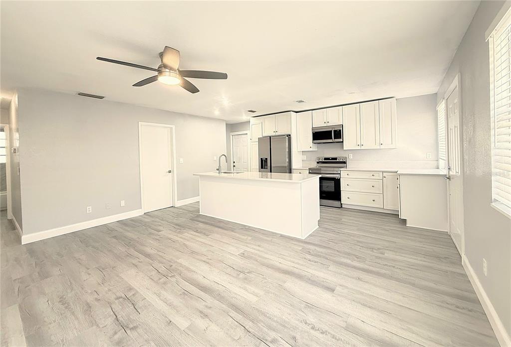 A kitchen with white cabinets, a central island, and light wood-look flooring — 1231 ILLINOIS AVENUE UNIT 1, PALM HARBOR, FL