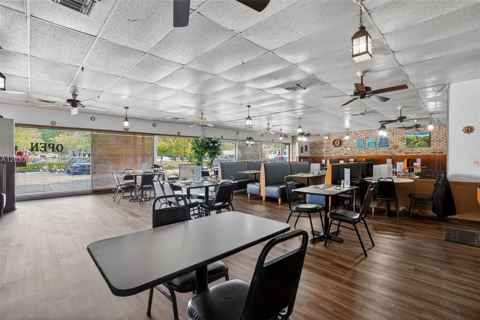 A restaurant interior features tables, chairs, booths, a brick wall, and a drop ceiling — Turnkey Pompano Beach Restaurant, Pompano Beach FL 33060, POMPANO BEACH, FL