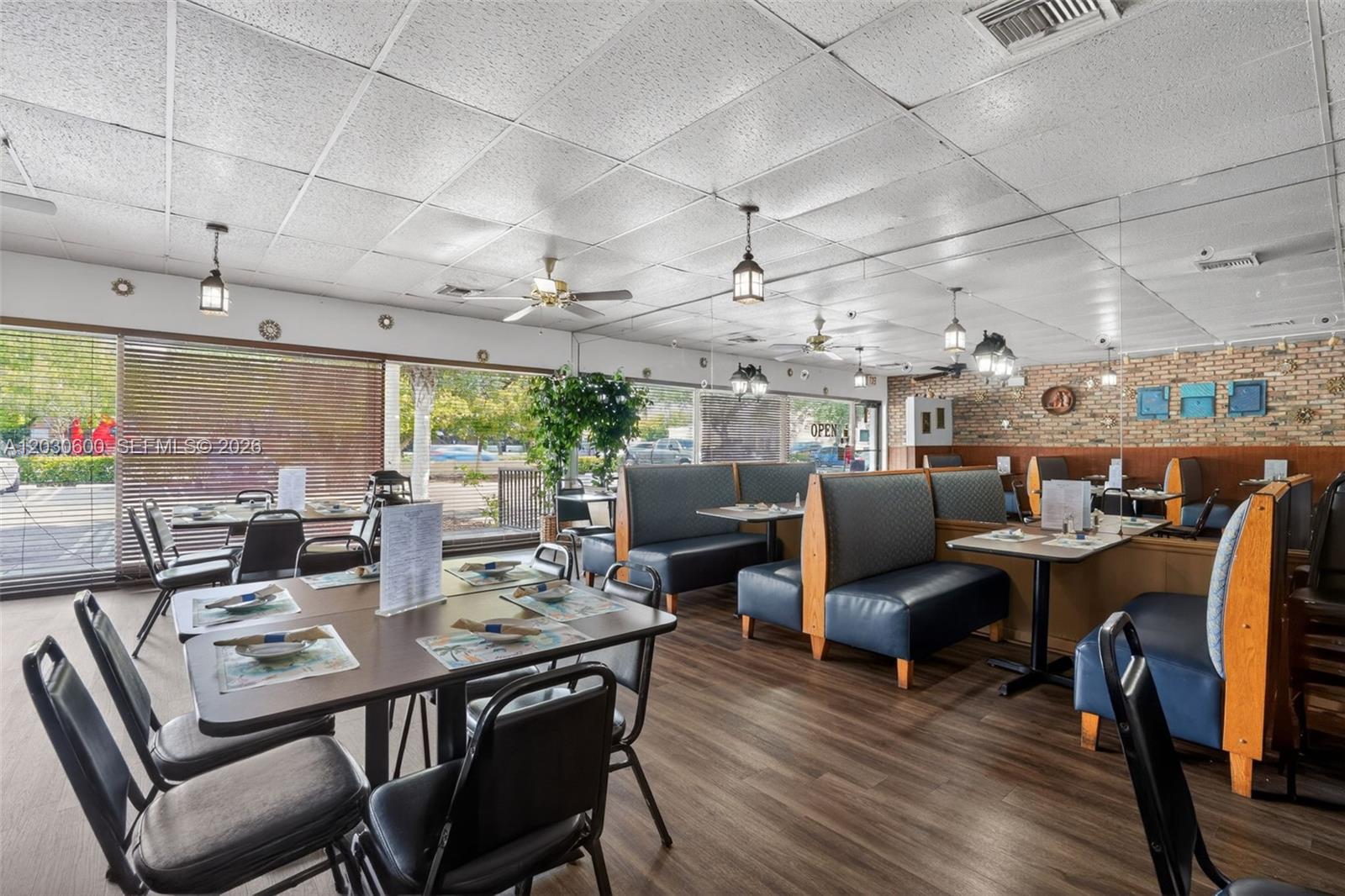 A restaurant dining room features blue booths, wooden tables, and a drop ceiling — Turnkey Pompano Beach Restaurant, Pompano Beach FL 33060, POMPANO BEACH, FL