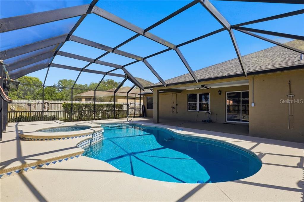 A swimming pool and spa are enclosed within a screened lanai behind a house — 20 BUTTERNUT, PALM COAST, FL