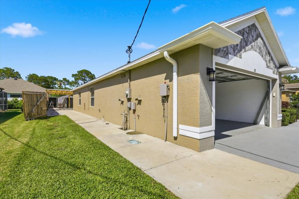 The side exterior of a house features a concrete driveway, a garage, and a lawn — 20 BUTTERNUT, PALM COAST, FL