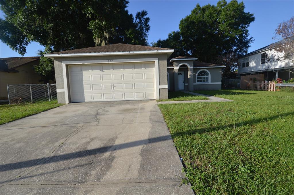 A single-story house with a two-car garage, a concrete driveway, and a front entryway — 622 CARIBOU COURT, POINCIANA, FL