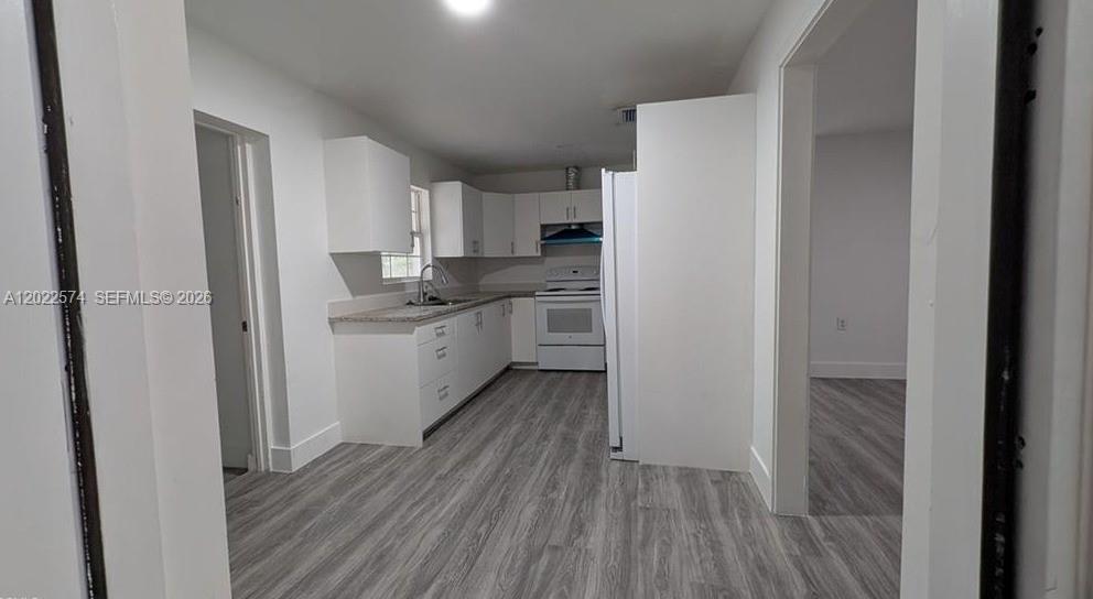 A kitchen with white cabinets, light countertops, and grey wood-look flooring — 660 S MISSOURI ST, La Belle FL 33935, LA BELLE, FL