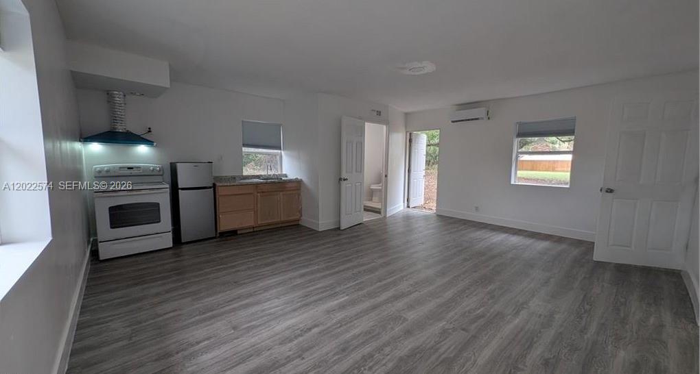 A studio apartment features a kitchenette, wood-look flooring, a bathroom door, and an exterior door — 660 S MISSOURI ST, La Belle FL 33935, LA BELLE, FL