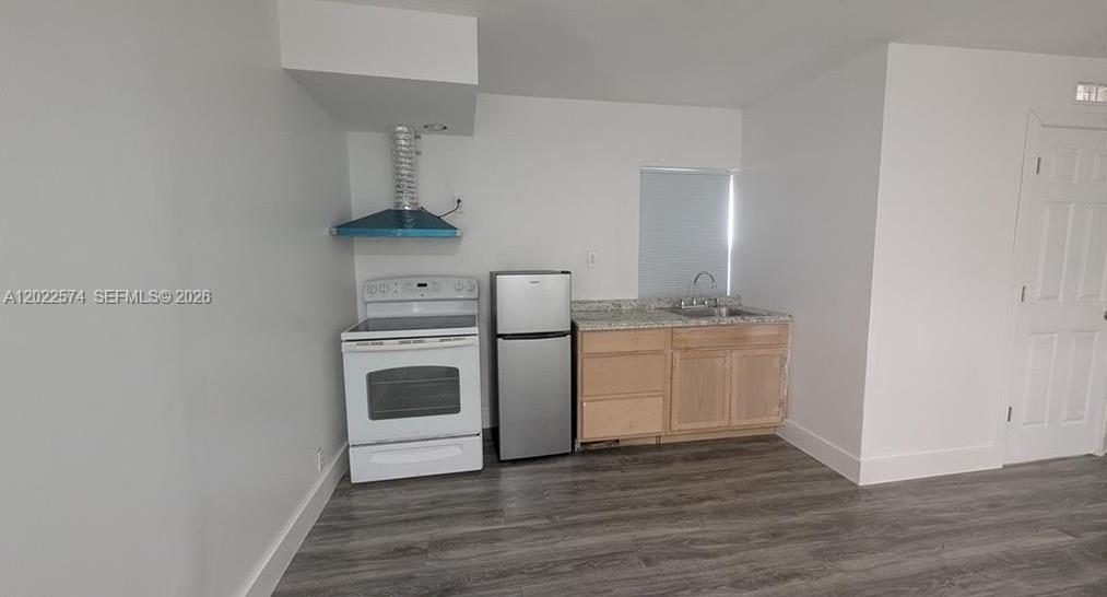 A small kitchen features white walls, wood-look flooring, a stove, a refrigerator, and wood cabinets — 660 S MISSOURI ST, La Belle FL 33935, LA BELLE, FL