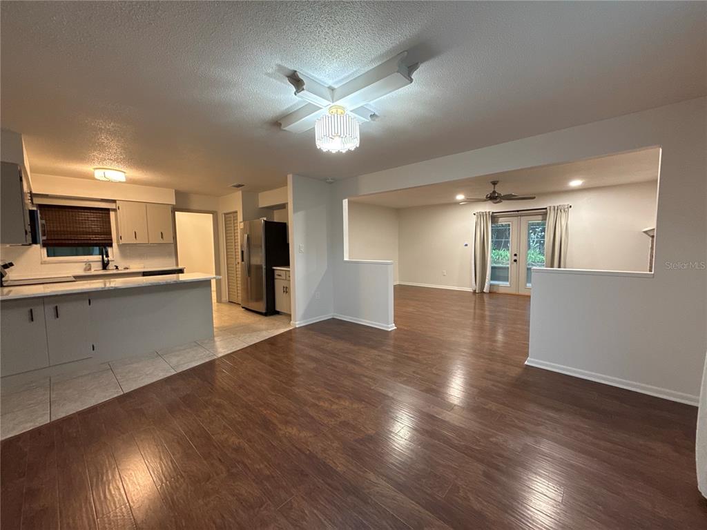 An open-concept living and kitchen area features wood-look flooring, white walls, and a chandelier — 1706 NE 4TH STREET, OCALA, FL