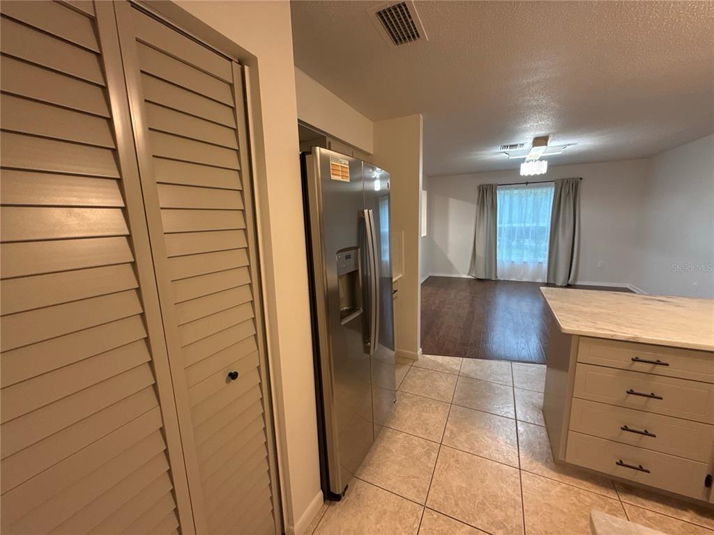 A kitchen with light-colored cabinets, stainless steel appliances, and tile flooring leads into a living area — 1706 NE 4TH STREET, OCALA, FL