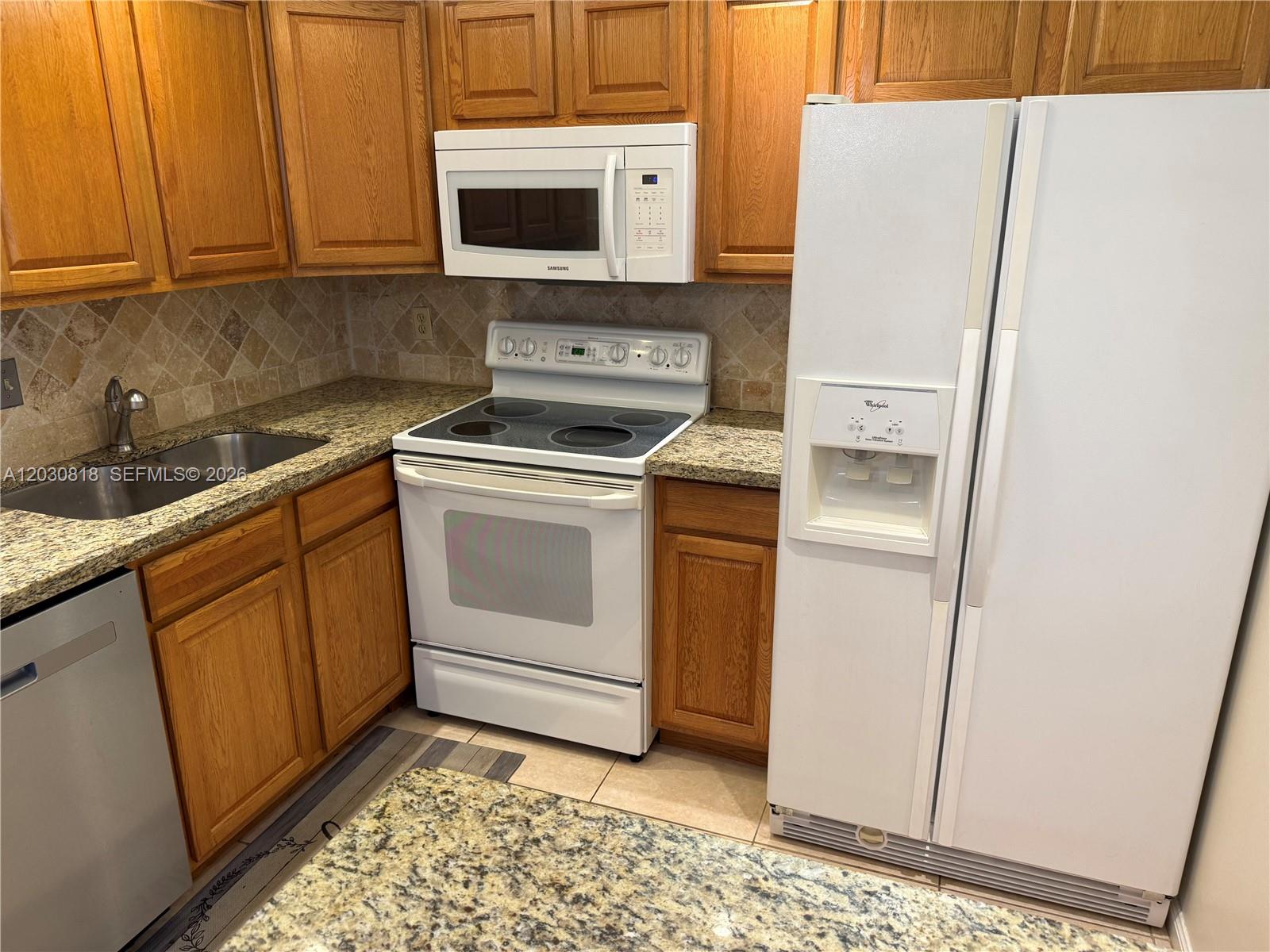 A kitchen features wood cabinets, granite countertops, a white stove, and a white refrigerator — 170 Cypress Club Dr # 729, Pompano Beach FL 33060, POMPANO BEACH, FL