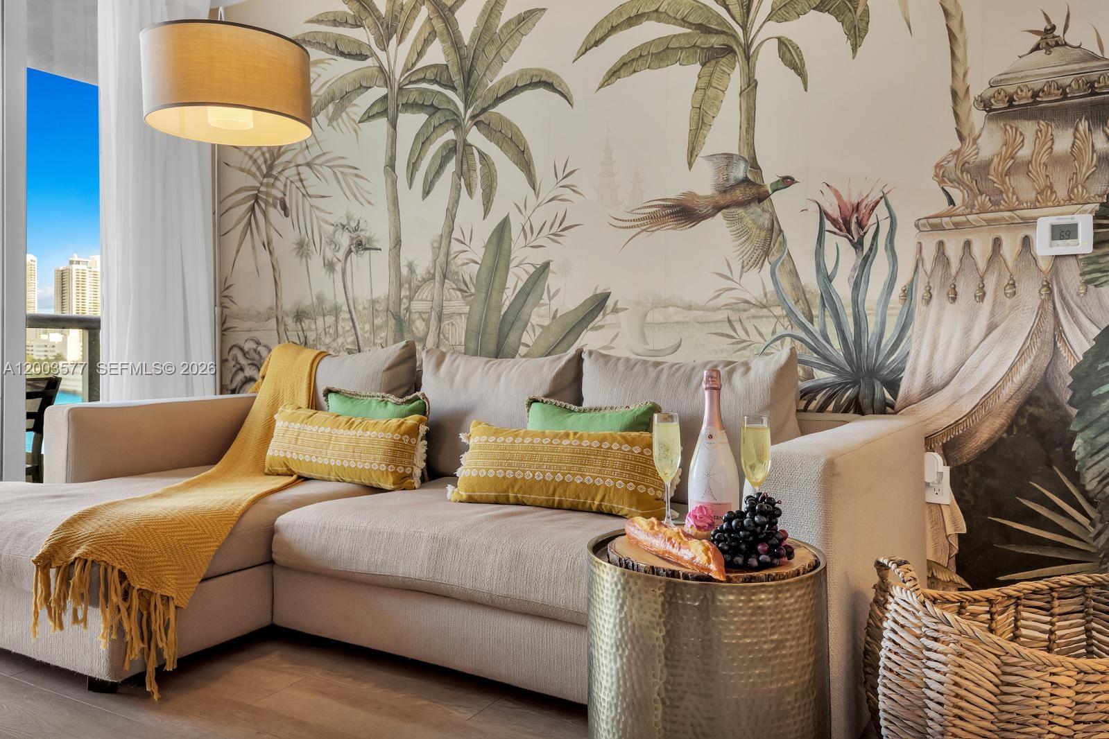 A living room features a beige sectional sofa, a mural wall, and a gold side table — 2602 E Hallandale Beach Blvd # R704, Hallandale Beach FL 33009, HALLANDALE BEACH, FL