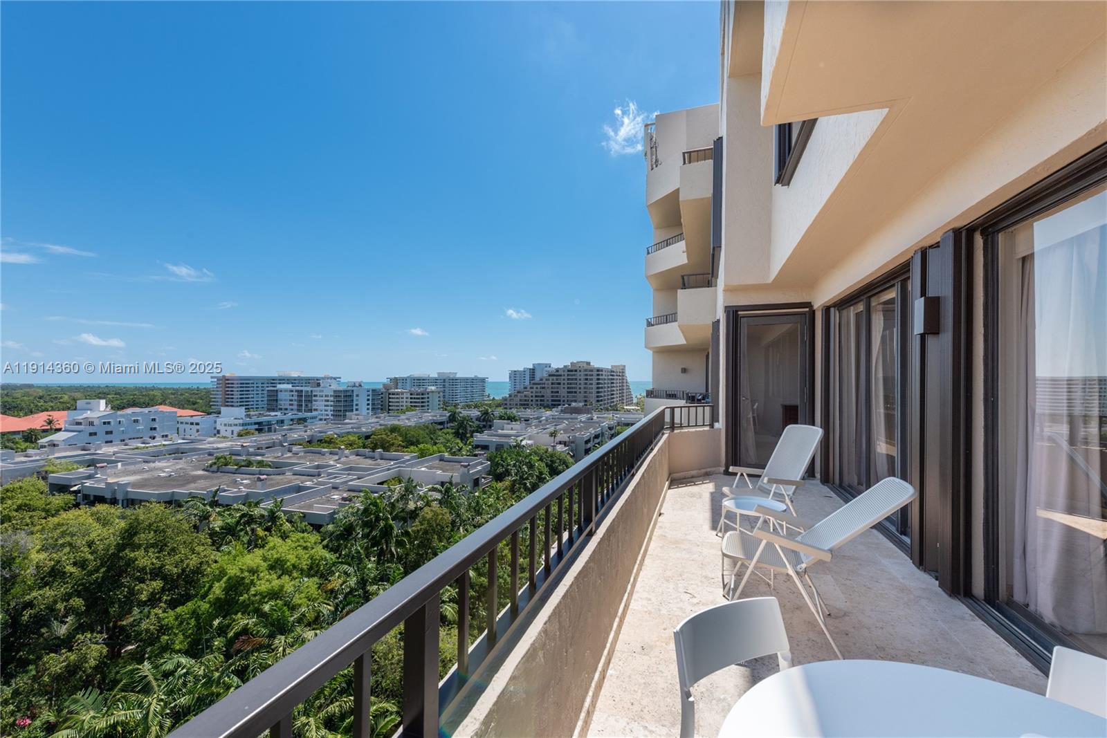 A balcony with outdoor furniture overlooks a residential neighborhood and distant ocean view — 151 Crandon Blvd # 1036, Key Biscayne FL 33149, KEY BISCAYNE, FL