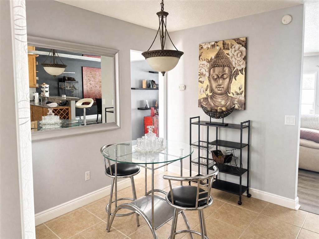 A dining area features a glass-topped table, two metal stools, a mirror, and Buddha wall art — 3520 STABLE RIDGE LANE, LAND O LAKES, FL
