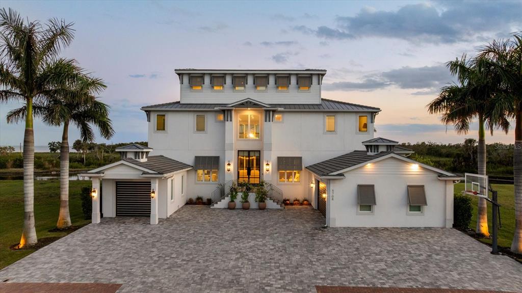 A large, three-story white house with a paved driveway and two palm trees — 5708 INSPIRATION TERRACE, BRADENTON, FL
