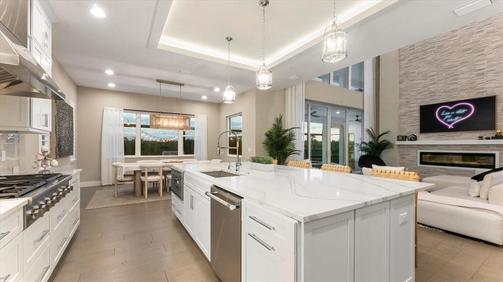 A modern kitchen features a white marble island, stainless steel appliances, and an adjacent dining area — 5708 INSPIRATION TERRACE, BRADENTON, FL