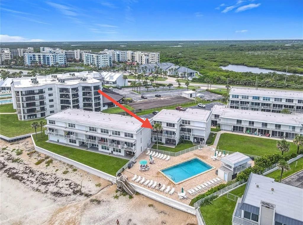 An aerial view shows a beachfront condominium complex with a swimming pool and parking lot — 4849 SAXON DRIVE UNIT A204, NEW SMYRNA BEACH, FL