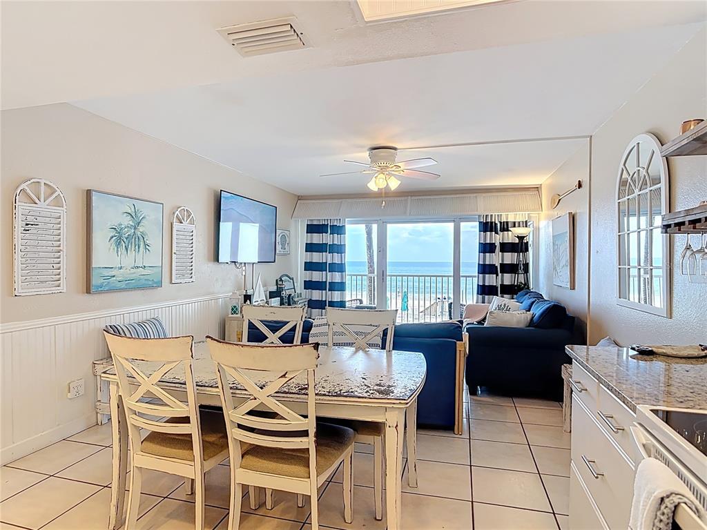 A dining area and living room with a view of the ocean through sliding doors — 4849 SAXON DRIVE UNIT A204, NEW SMYRNA BEACH, FL