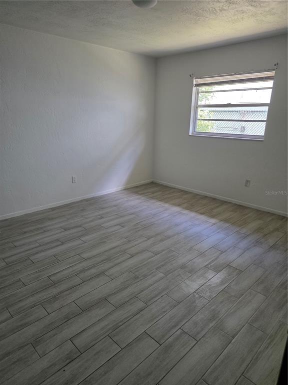 An empty bedroom features white walls, a single window, and light-colored wood-look tile flooring — 830 N CLAKE STREET UNIT 1, DELAND, FL