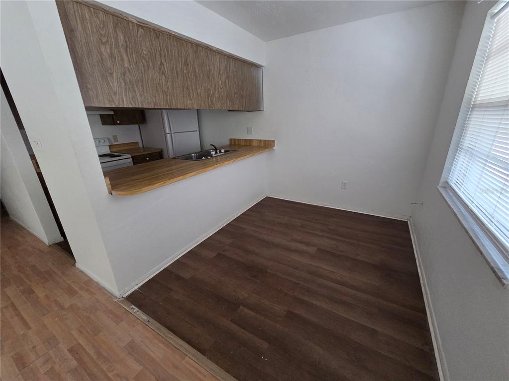 A dining area with dark wood-look flooring features a breakfast bar overlooking a small kitchen — 830 N CLAKE STREET UNIT 1, DELAND, FL