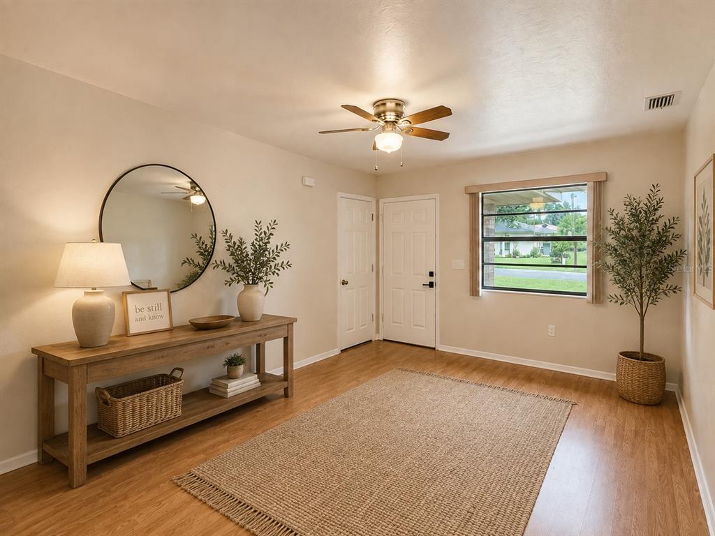 An entryway features a wooden console table, a round mirror, and a large area rug — 3524 BRISTOL STREET, SEBRING, FL