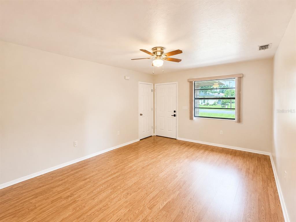 An empty room with light-colored walls, wood-look flooring, a ceiling fan, and two doors — 3524 BRISTOL STREET, SEBRING, FL