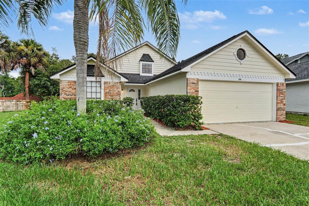 A single-story house with a beige exterior, brick accents, a two-car garage, and landscaping — 2361 ROANOKE COURT, LAKE MARY, FL