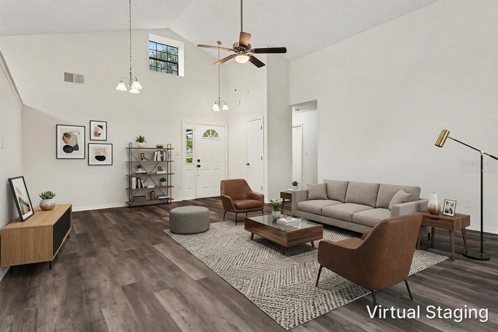 A living room with vaulted ceilings, wood-look flooring, and virtual staging furniture — 2361 ROANOKE COURT, LAKE MARY, FL