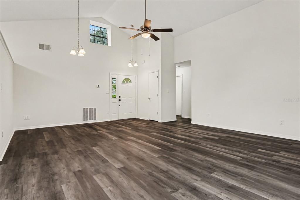An empty living room with vaulted ceilings, a ceiling fan, and dark wood-look flooring — 2361 ROANOKE COURT, LAKE MARY, FL