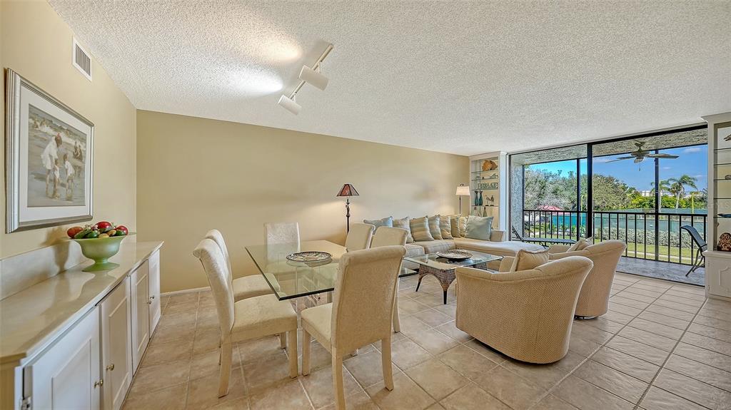 A combined dining and living area features tile floors, a glass table, and a balcony — 1975 GULF OF MEXICO DRIVE UNIT 208, LONGBOAT KEY, FL