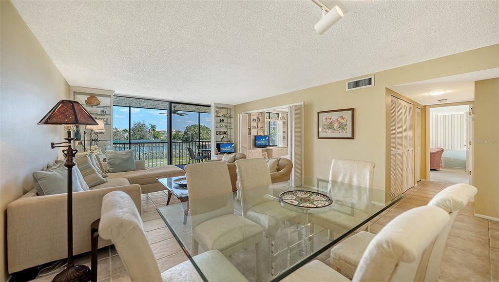 A living and dining area with tile floors, a glass table, and a balcony view — 1975 GULF OF MEXICO DRIVE UNIT 208, LONGBOAT KEY, FL