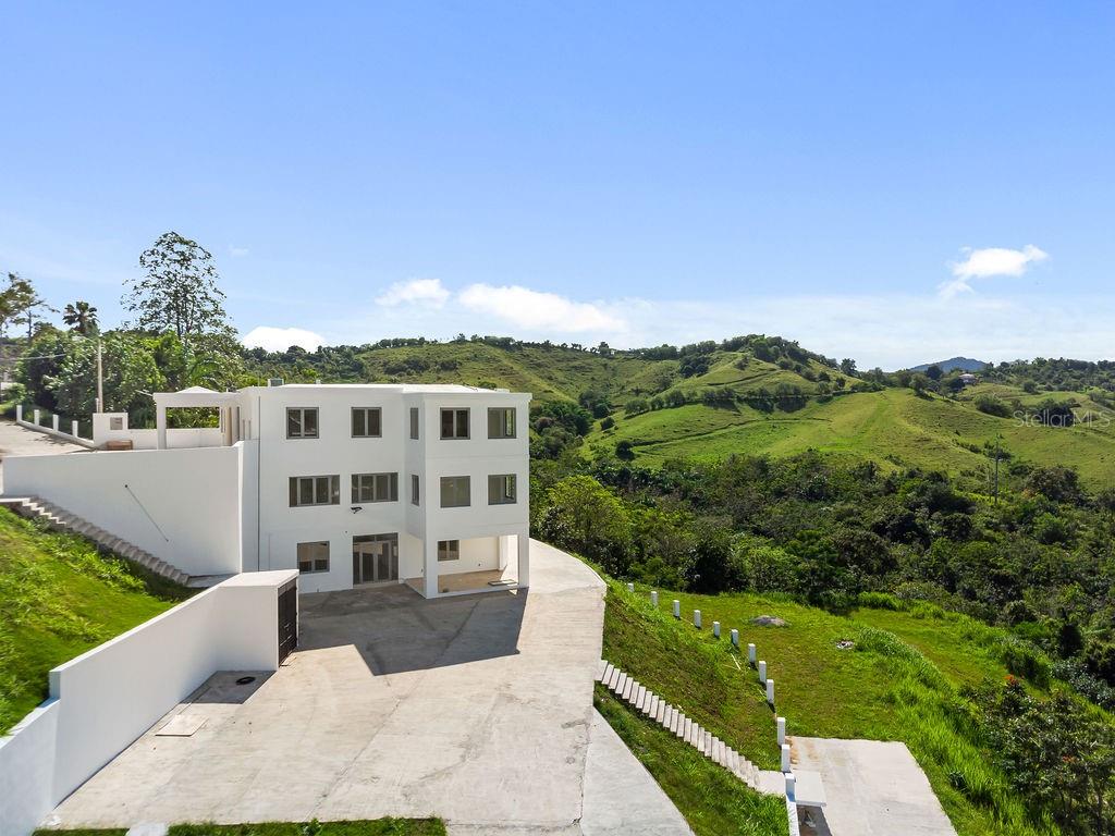A three-story white house sits on a hillside overlooking a green, mountainous landscape — CARR 171 MOGOTE, CAYEY, PR
