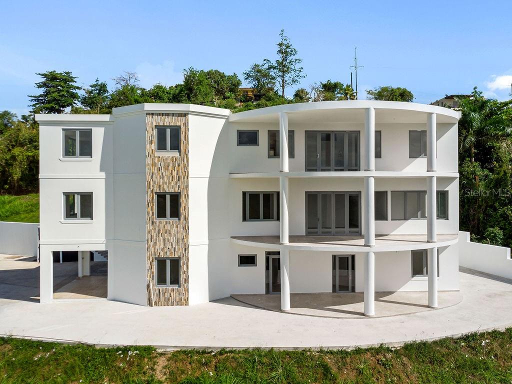 A modern three-story white house with a curved facade, stone accents, and open balconies — CARR 171 MOGOTE, CAYEY, PR