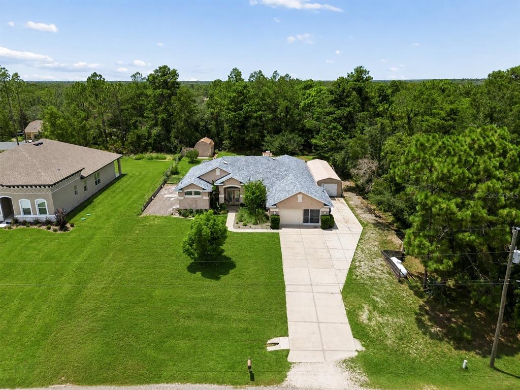 An aerial view shows a single-story house with a concrete driveway and a large yard — 8293 NITTANY ROAD, WEEKI WACHEE, FL