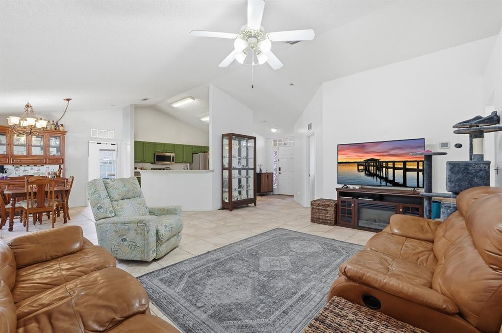 A living room with tile floors, a ceiling fan, and a view into the kitchen — 36 LEMA LANE, PALM COAST, FL