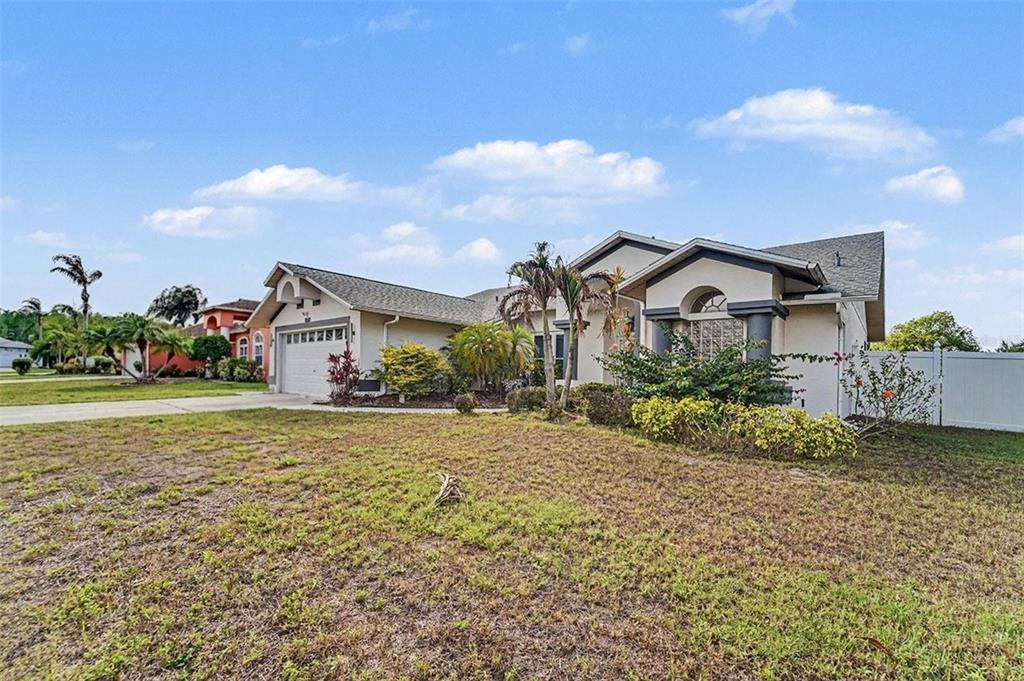 A single-story house with a beige stucco exterior, a two-car garage, and a front lawn — 8511 SIAMANG COURT, NEW PORT RICHEY, FL