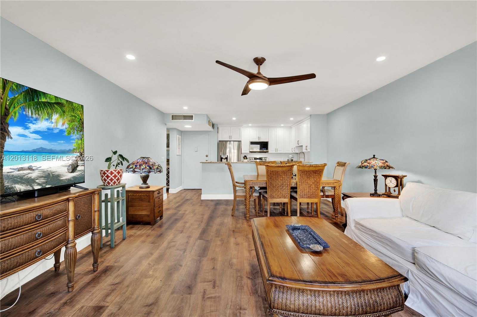 An open-concept living and dining area features light blue walls, wood flooring, and white cabinetry — 1516 S Lakeside Dr # 105, Lake Worth FL 33460, LAKE WORTH, FL
