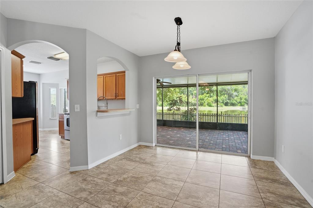A dining area with tile flooring, a hanging light fixture, and sliding doors to a patio — 9913 EDMONTON DRIVE, LAND O LAKES, FL