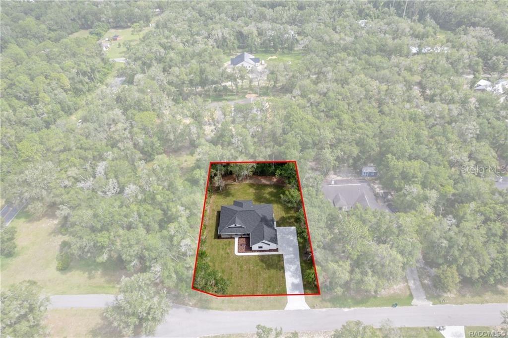 An aerial view shows a single-story house situated on a wooded residential lot — 2961 E ANGELINA STREET, INVERNESS, FL