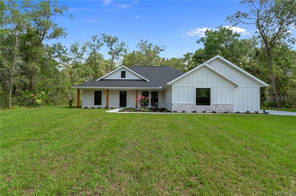 A white farmhouse-style house with a dark roof sits on a grassy lot — 2961 E ANGELINA STREET, INVERNESS, FL
