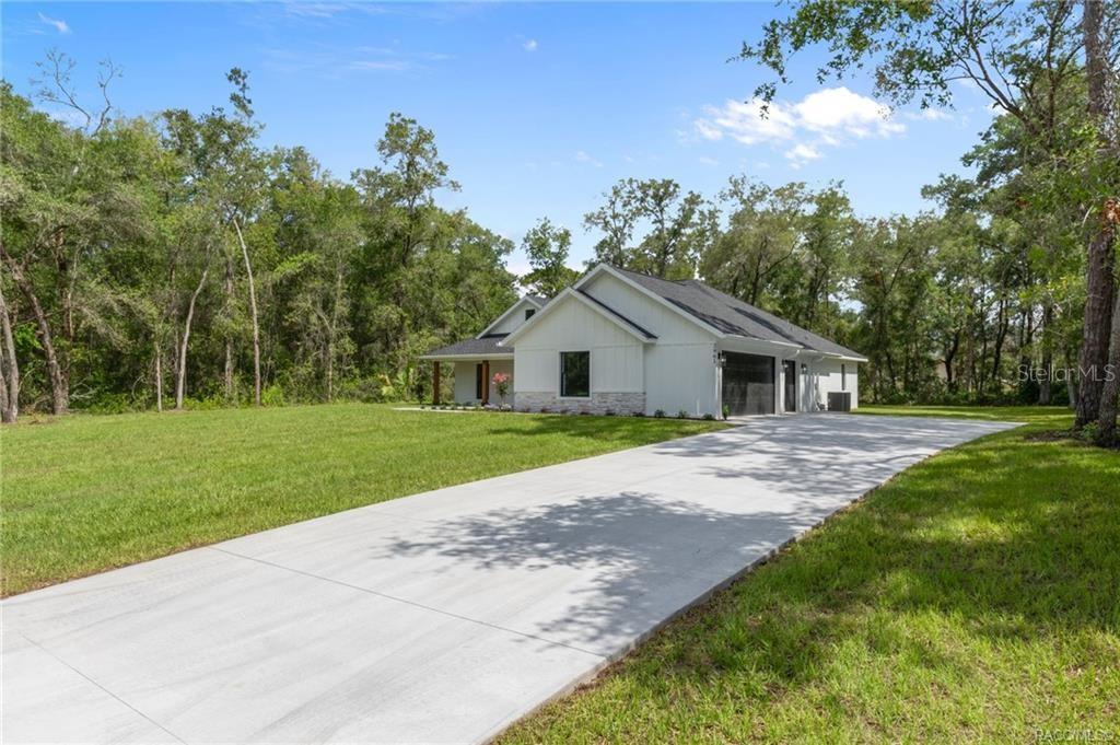 A white modern farmhouse with a stone base and a long concrete driveway — 2961 E ANGELINA STREET, INVERNESS, FL