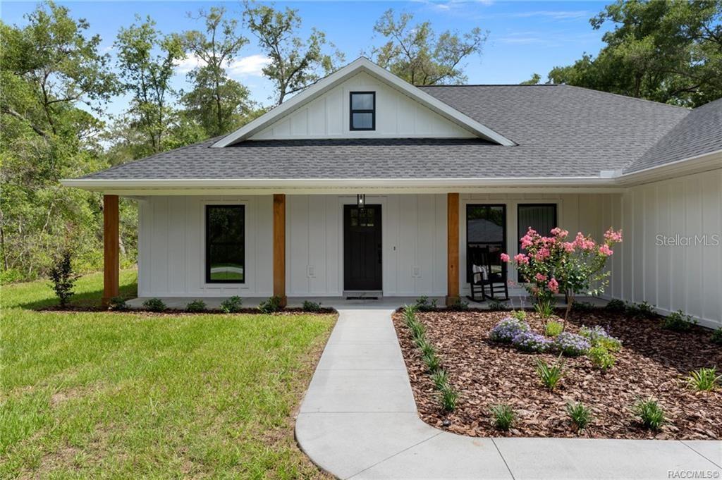 A white farmhouse-style home features a covered porch with wood columns and black window frames — 2961 E ANGELINA STREET, INVERNESS, FL