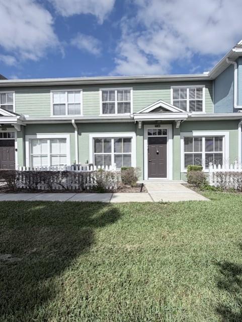 A two-story townhouse with light green siding, white trim, and a small front yard — 2201 SAN VITTORINO CIRCLE UNIT 106, KISSIMMEE, FL
