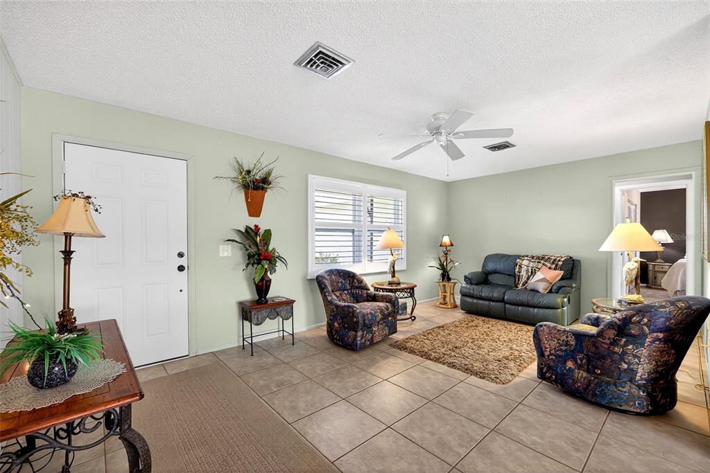 A living room features tile flooring, a ceiling fan, and two patterned armchairs — 1255 LINCOLN DRIVE, ENGLEWOOD, FL