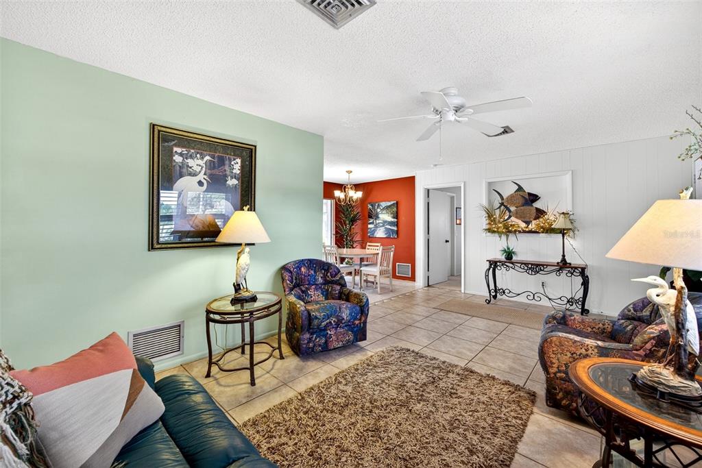 A living room with tile floors, a patterned armchair, and a view into a dining area — 1255 LINCOLN DRIVE, ENGLEWOOD, FL