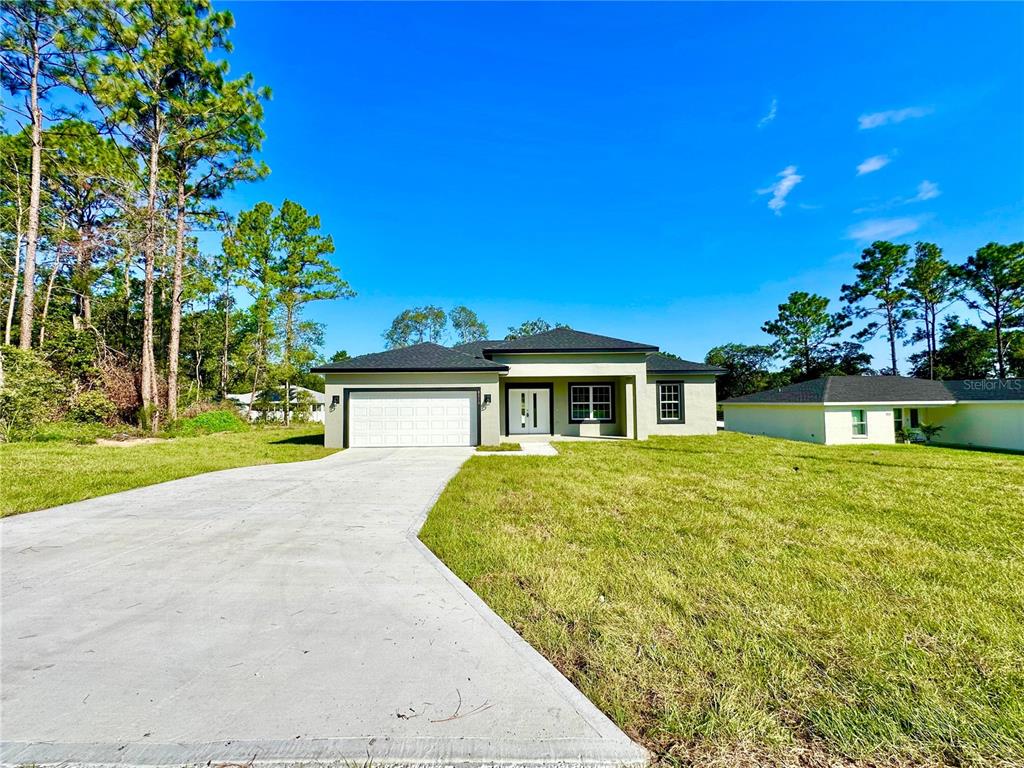 A single-story house with a white garage and a concrete driveway sits on a lawn — 8010 N POCONO DRIVE, CITRUS SPRINGS, FL