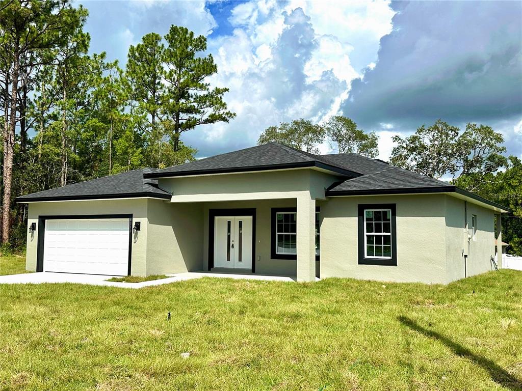 A single-story house with a light green exterior, black trim, and a two-car garage — 8010 N POCONO DRIVE, CITRUS SPRINGS, FL