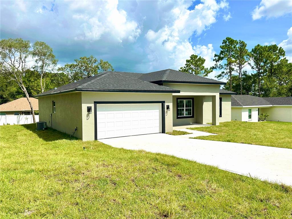 A single-story house with a white garage door, light-colored stucco exterior, and a concrete driveway — 8010 N POCONO DRIVE, CITRUS SPRINGS, FL