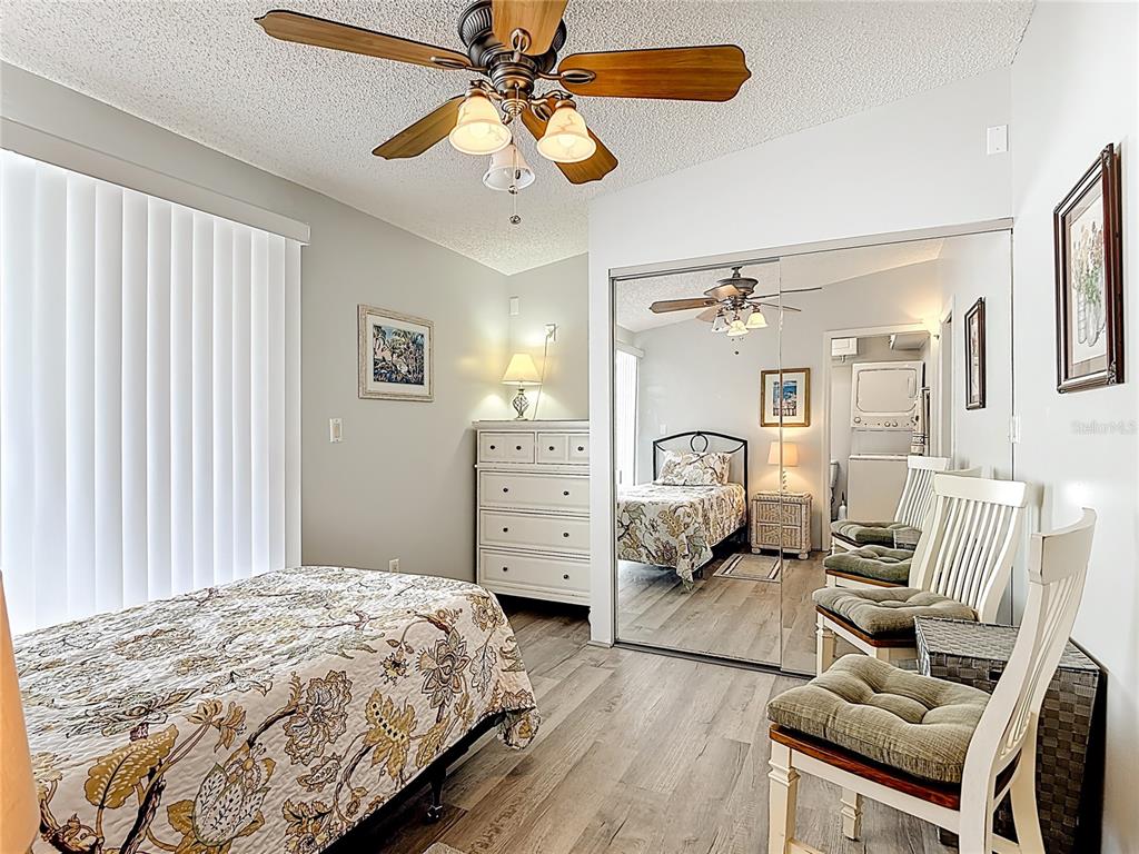 A bedroom features a bed, a dresser, a mirrored closet, and chairs on wood flooring — 9000 US HWY 192 # 545, CLERMONT, FL
