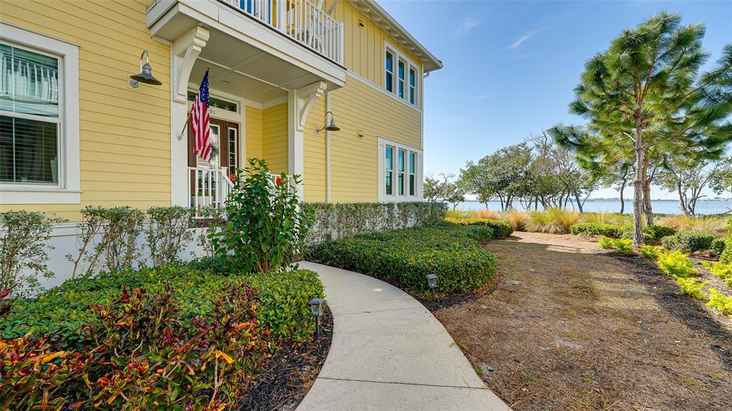 A yellow house with a concrete walkway leads to a front porch near the water — 280 SAINT LUCIA DRIVE UNIT 101, BRADENTON, FL