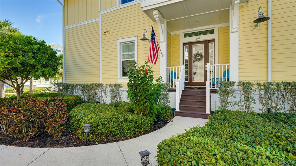 A yellow house with a front porch, American flag, and landscaped yard — 280 SAINT LUCIA DRIVE UNIT 101, BRADENTON, FL